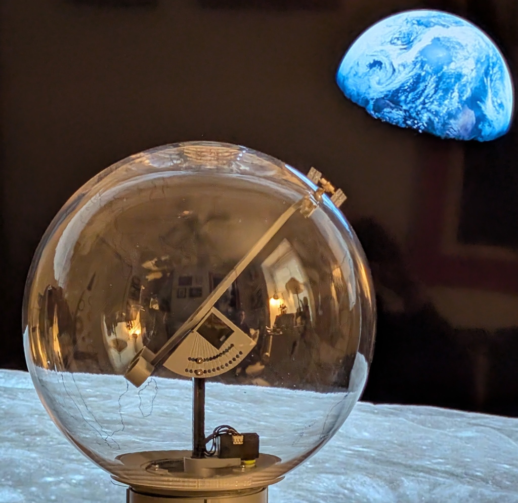 Orbigator against a lunar surface projection with Earth visible